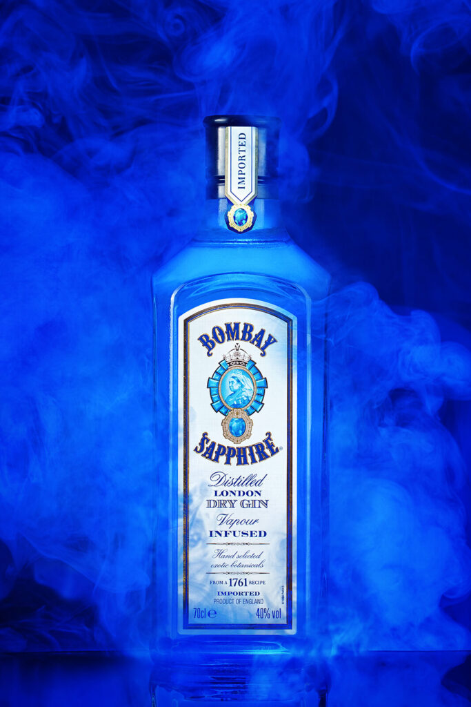 Bombay Sapphire cin şişesi, sanatsal mavi duman fonuyla.
