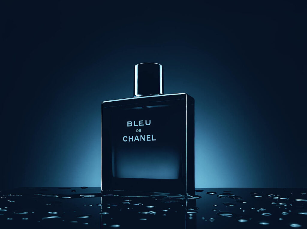 Bleu de Chanel parf&uuml;m şişesi, su yansımalarıyla l&uuml;ks still life kompozisyonunda.