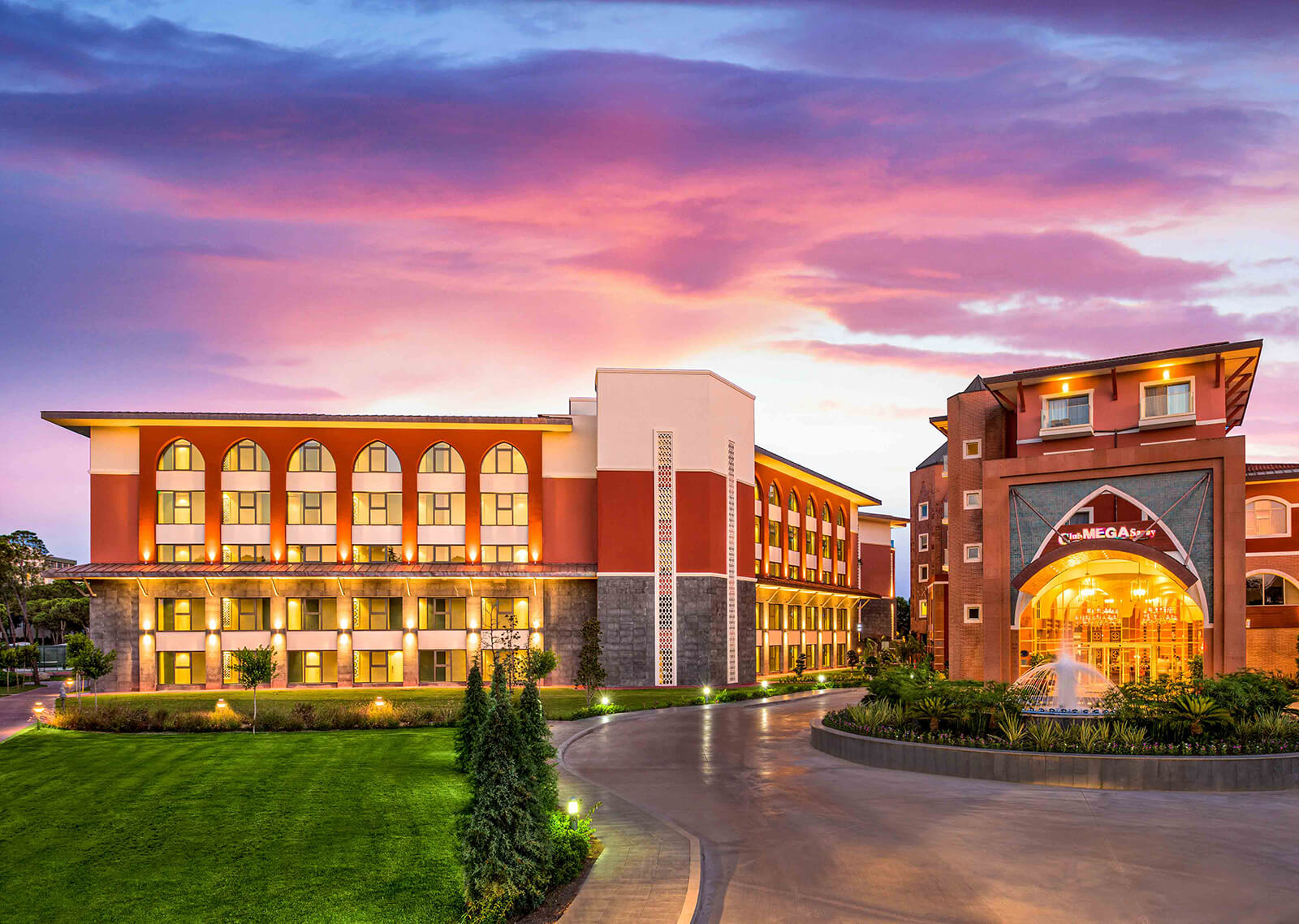 Exterior view of Club Mega Saray hotel in Antalya with vibrant sunset sky