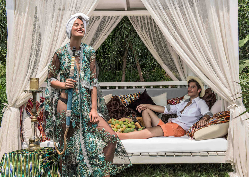 A luxurious outdoor cabana at Delphin Hotel in Antalya with a woman enjoying a hookah and a man relaxing on a daybed.