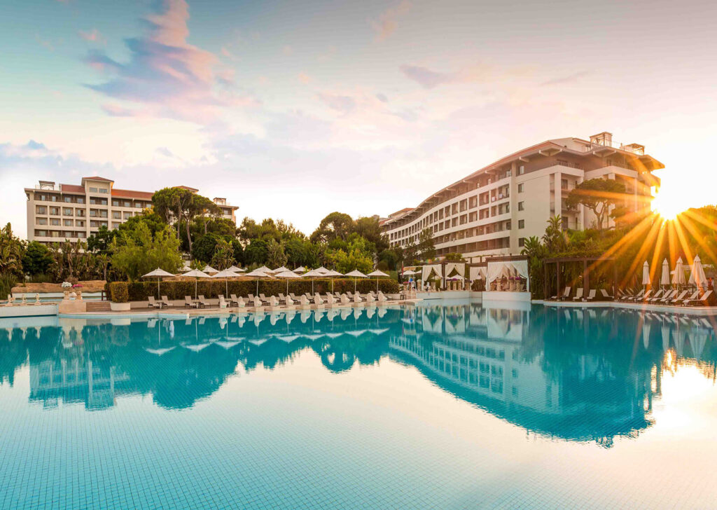 Sunset over the pool at Ela Quality Hotel with loungers and umbrellas in Antalya