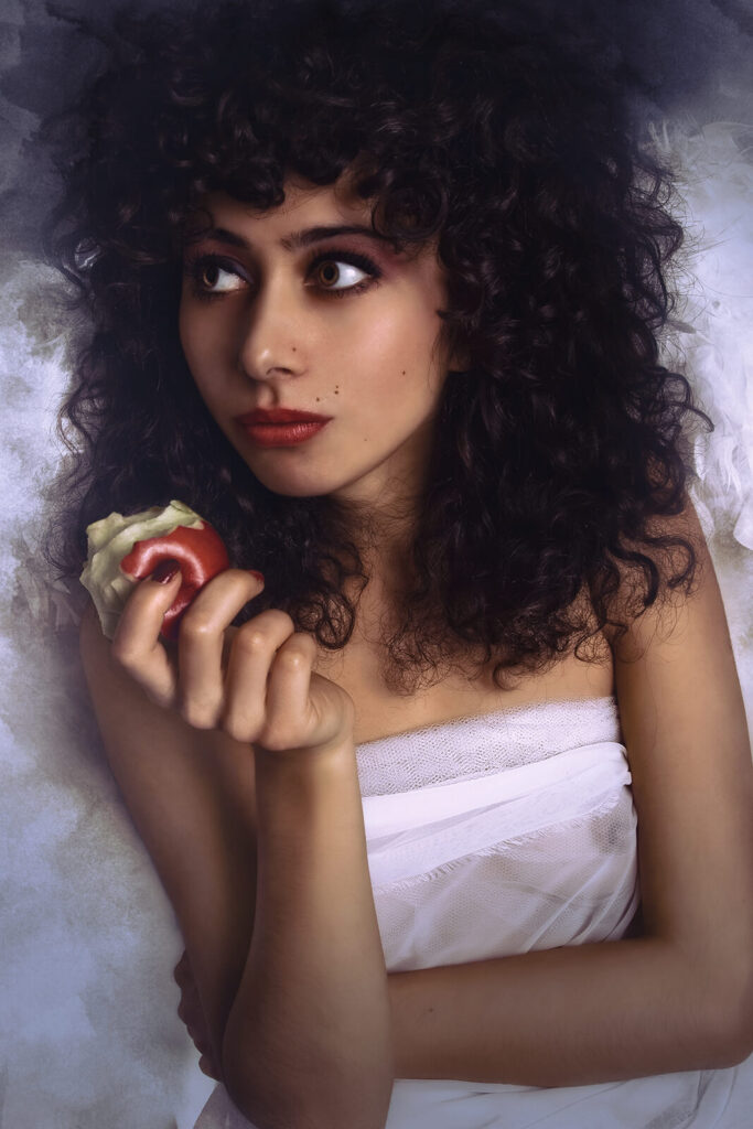 A fallen angel depicted in a surreal portrait holding a bitten red apple.