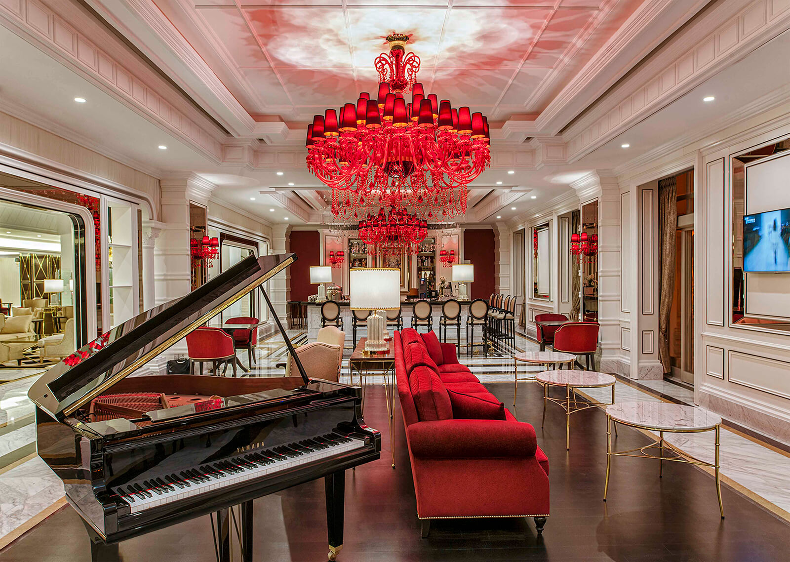 Luxurious lounge at Kaya Artemis Resort in Cyprus with a grand piano and elegant chandeliers.