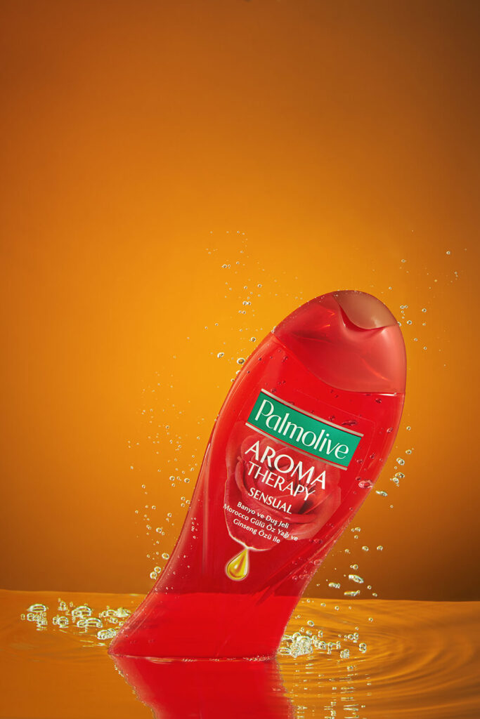 Fas g&uuml;l&uuml; yağı ve ginseng &ouml;z&uuml;n&uuml;n l&uuml;ks dokusunu vurgulayan, altın rengi suya sı&ccedil;rayan Palmolive Aroma Therapy Sensual duş jeli şişesi.