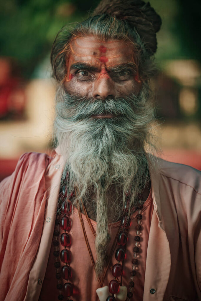 A close-up portrait of a sadhu in India with piercing eyes, sacred forehead markings, and traditional attire.